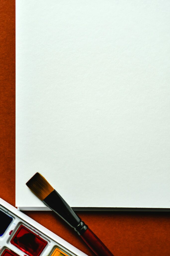 Close-up of painting materials: paintbrush, watercolor set, and blank canvas ready for artistic creativity.